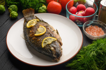 Stewed fish with lemons and fresh vegetables. Delicious and healthy food.