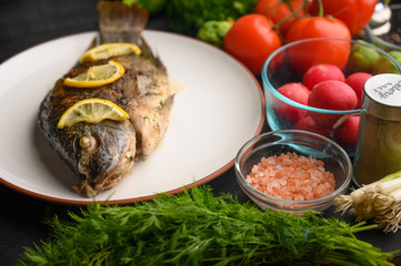 Grilled fish with fresh vegetables, on a wooden black background. I also eat healthy food. Seafood, Eastern or European cuisine.