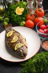 Cooked fish with ingredients, on black background. Vertical frame.