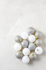 Overhead flat lay shot of a group of Christmas Tree ornaments on a light gray surface with copy space.