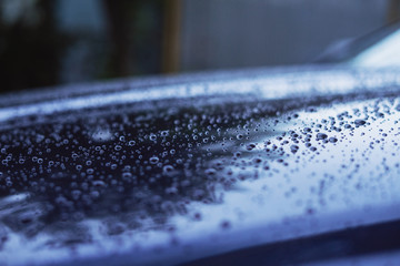 Water drops on the surface of a blue car in cold colors
