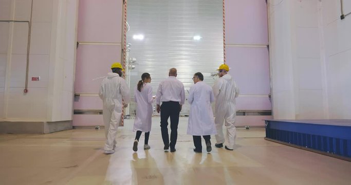 Chief and his scientists and employees entering large innovative high voltage laboratory. Scientific delegation visit new plant, discussing international cooperation