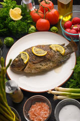 Cooked fish with ingredients, on black background. Vertical frame.