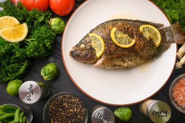 Grilled fish with fresh vegetables, on a wooden black background. I also eat healthy food. Seafood, Eastern or European cuisine.