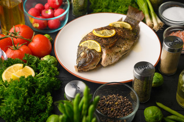 Grilled fish with fresh vegetables, on a wooden black background. I also eat healthy food. Seafood, Eastern or European cuisine.