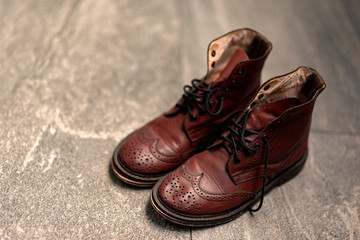 Horizontal shot of brown combat boots standing on surface. Concept of tiresome and experience