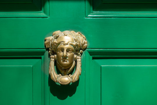 face figure brass front door knicker on a bright green door Stock Photo