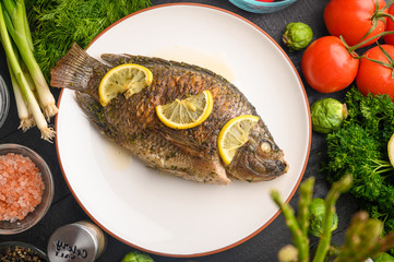 Stewed fish with lemons and fresh vegetables. Delicious and healthy food.