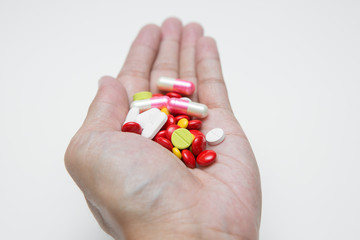 Selective focus of Many medicine capsules on hand  on white background