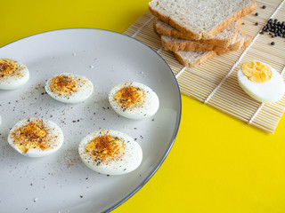 ฺBoiled egg topped with Cayenne pepper Pepper and Salt on a white dish,Egg colors white and...