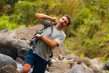 young happy and attractive man with travel backpack hiking in river at forest feeling free enjoying nature and fresh environment on summer trekking journey