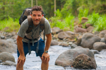 young happy and attractive man with travel backpack hiking in river at forest feeling free enjoying nature and fresh environment on summer trekking journey