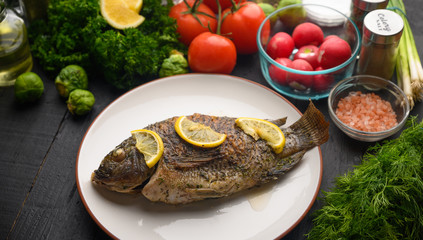 Eastern or European cuisine, Fried fish with fresh vegetables, on a wooden black background. I also eat healthy food. Seafood, recipe book, selling fish, restaurant business