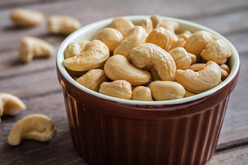 Cashew nut in brown bowl on wooden table