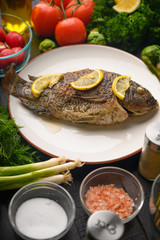 Cooked fish with ingredients, on black background. Vertical frame.