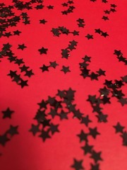 Black star confetti on red background 