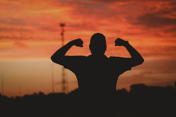 Silhouette of strong man flexing his muscles 