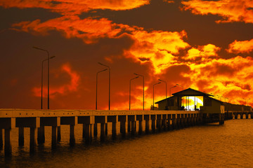 Obraz premium sunset sky red cloud on pavilion on pier and silhouette light poles