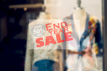 Window display with text end of year sale banner background on fashion store showcase with mannequins in shopping mall.blurred background.shopping concept