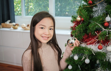The little girl holding chrismat ball to over the Christmas tree. - 308622071