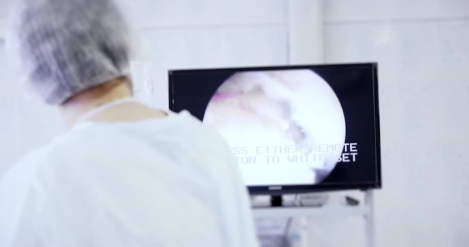 Back view of surgeon looks at monitors while preforming operation using surgical laparoscopy instruments. Medicine, surgery, health care concept. Filmed on RED 4k, 10 bit color space
