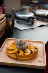 waffles with peach and ice cream put on wooden plate