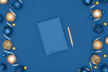 New Year and Christmas decorations and notebook and pen on blue background. Wish list or goals concept. Top view, flat lay, copy space. Trendy color of the year 2020.