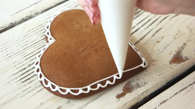 Decoration of Valentines Day cookie. Decorating homemade gingerbread cookies with icing from piping bag. Desserts for Valentines Day.