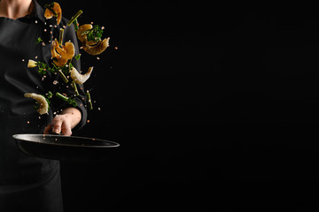Seafood, frying shrimp with vegetables, a chef on a black background. Advertising banner for the...