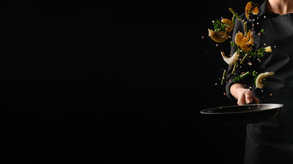 Seafood, frying shrimp with vegetables, a chef on a black background. Advertising banner for the...