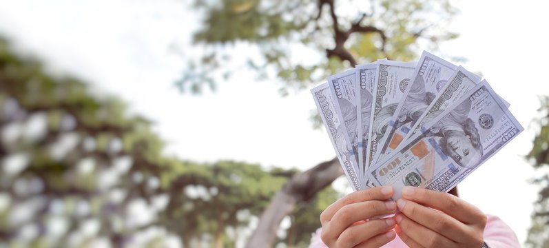 Hand showing 100 dollars cash money banknotes, bonus or commission extra money in end of festival for working woman, micro job or online shopping seller in digital marketing concept or cash flow