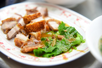 Crispy Pork Belly Stir Fry With Chinese Kale in white plate at restaurant