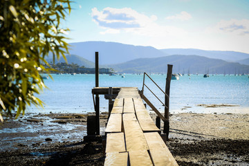 Fototapeta premium Late afternoon view of small rustic wooden jetty at Mandalay off Airlie Beach when the tide is out