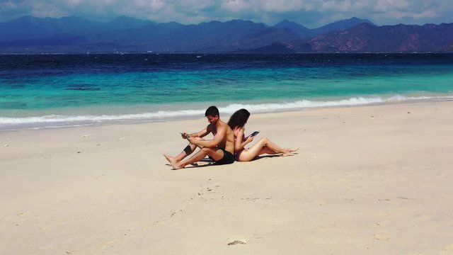 young couple relaxing on the summer breeze on the tropical sandy beach and reading books