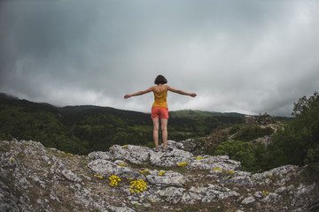 A girl stands on top of a mountain.