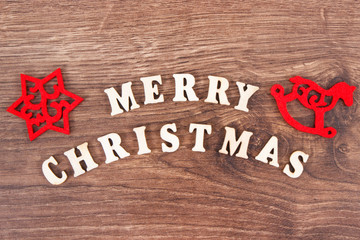 Inscription Merry Christmas with red decorations on rustic board, festive time concept