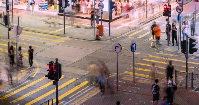 Time lapse of busy street intersection with traffic and pedestrians at night in Hong Kong.