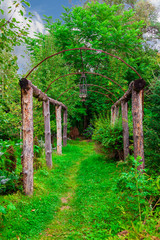 A wooden arched tunnel surrounded by green trees and plants with leaves at a summer day. Green way to destination, achieving goals. Nature and environment.