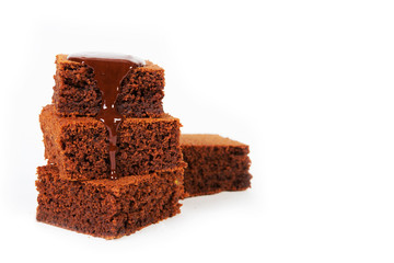 Pieces of traditional Belgian chocolate biscuit brownie lies pyramid, poured melted warm chocolate, on a white background. Horizontal photo with copy space.