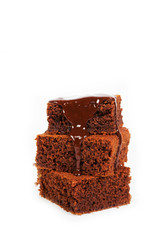 Pieces of traditional Belgian chocolate biscuit brownie lies pyramid, poured melted warm chocolate, on a white background. Vertical photo with copy space.