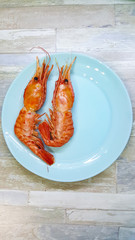 Seafood boiled wild tiger prawns close up on a blue plate on the table. the view from the top.