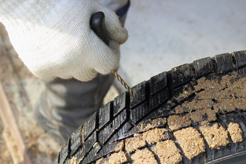 Repairman hand in a work glove cleans the vehicle tyre puncture with an awl