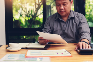 Fototapeta premium Small and Medium Enterprise Business concept of ,Businessman using calculator to calculate Assets Chart