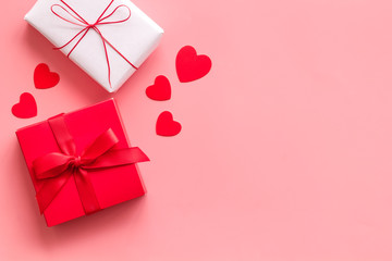 Present to a lover on Valentine's Day. Gift boxes near paper hearts on pink background top-down frame copy space