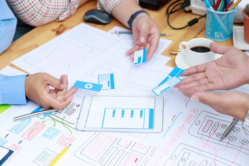 Graphic designers work together with UX UI designer planning application template layout framework for mobile phone computer mobile