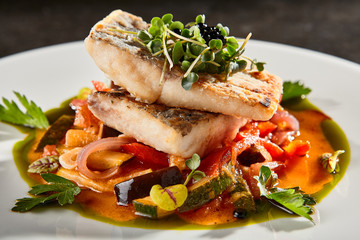 Pollock fish fillet with vegetables on white plate