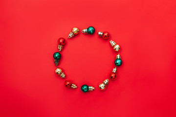 christmas composition. round frame made of red christmas balls on red background. Copy space for text in centre. flat lay