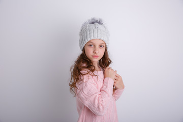 little girl in knitted winter hat on white background