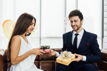 Young couple celebrating new year together, exchanging gifts to each other.