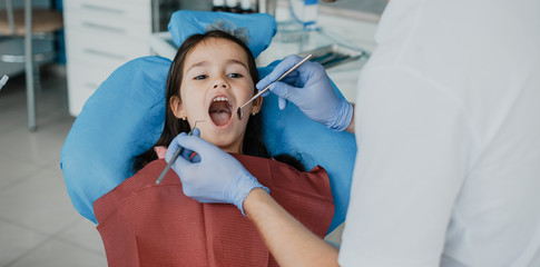 Cute little girl having a teeth surgery by a pediatric stomatologist .